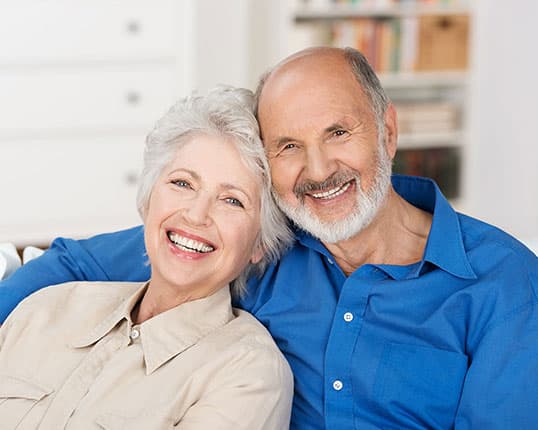 Smiling older couple enjoying confident smiles after dental implant treatment